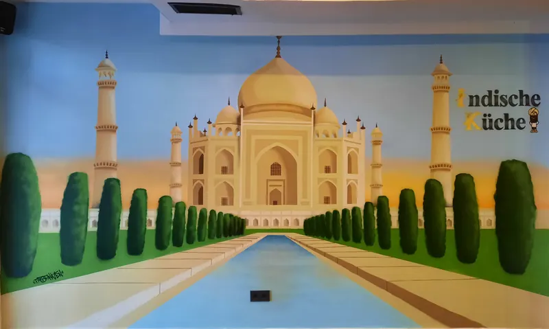 Restaurantwand mit gesprühtem Taj Mahal, Wasserbecken, Zypressenreihen und dem Schriftzug Indische Küche