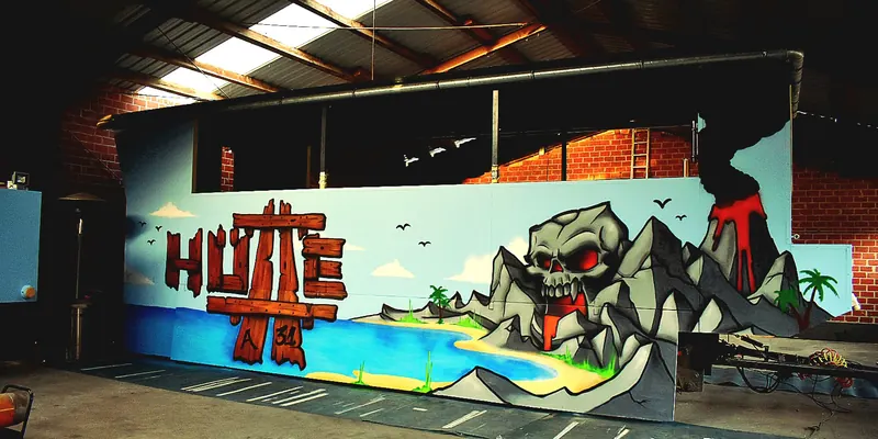 Theke in einer Halle mit Graffiti: Schriftzug Hütte, Meer, Strand und Vulkan in Totenkopfform