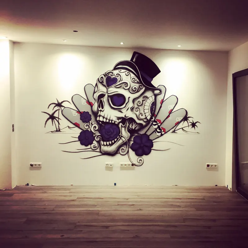 Weiße Wand mit verziertem Totenkopf mit Zylinder, violetten Rosen und Palmen